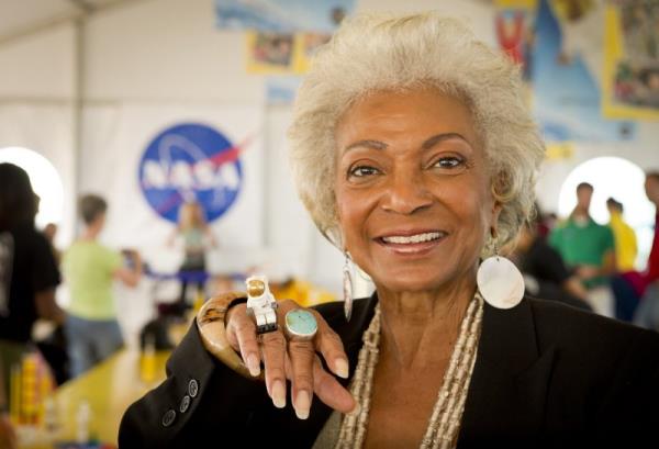 woman smiling at camera showing jewelry nasa logo in background