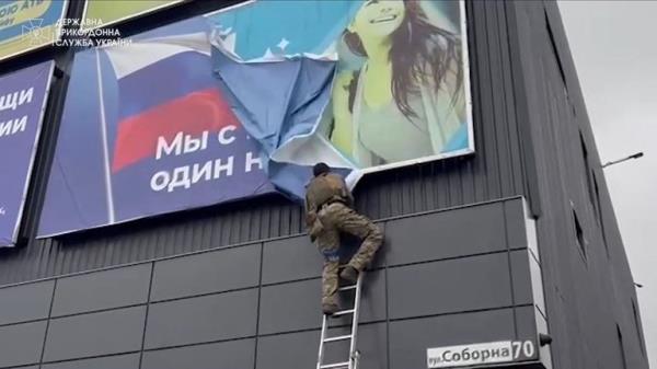A Ukrainian soldier rips down a Russian banner, in Vovchansk
Pic: State Border Service of Ukraine